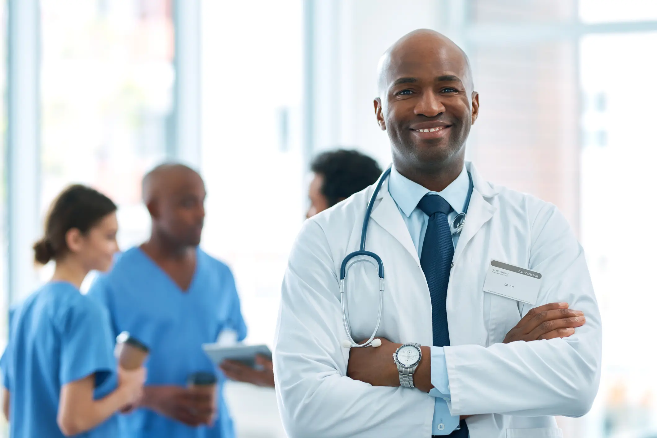 Portrait of a mature doctor standing in a hospital with his colleagues in the background